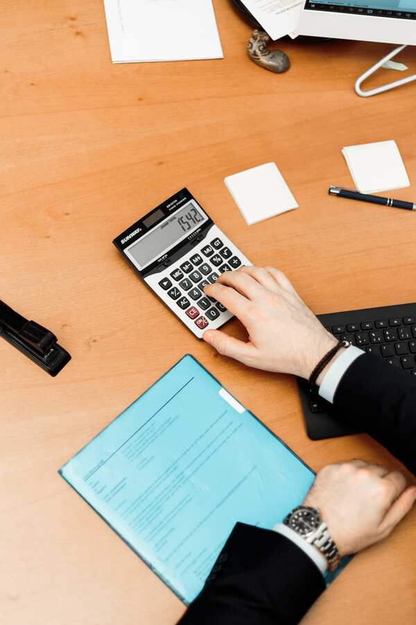 Homme sur un bureau avec une calculatrice, un bloc note et un document
